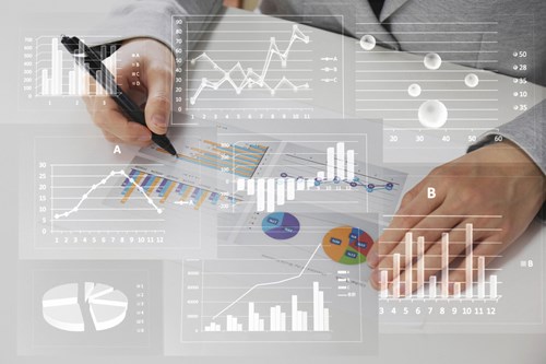 A fleet manager edits diagrams printed out with a ballpoint pen. Semi-transparent white diagrams of various shapes (including bar charts, line charts and pie charts) are superimposed on the photo.