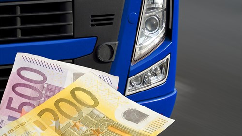 A 500-euro bill and a 200-euro bill in front of a truck symbolize that non-compliance with regulations can quickly become expensive.
